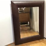 A large wall mirror with a padded faux alligator skin frame (101cm x 80cm)