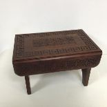 A carved Indian stool, the rectangular top with a stylised central leaf and flower motif, within a