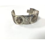 A Chinese white metal alternating figure and character panel bracelet with a snap fastening and