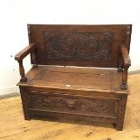 An early 20thc carved oak monk's bench, the hinged back/seat within arms with baluster supports