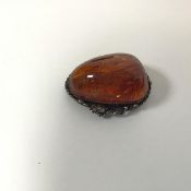 A white metal mounted amber brooch of asymmetrical form with twisted wire decoration (2cm x 4cm)