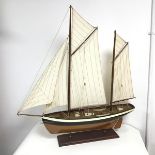A model yacht, two masted gaff rigged complete with sails, rigging, windlass and row boats, on a