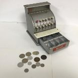 A child's cash register by Merit, c.1950, includes a small collection of British and Foreign coins