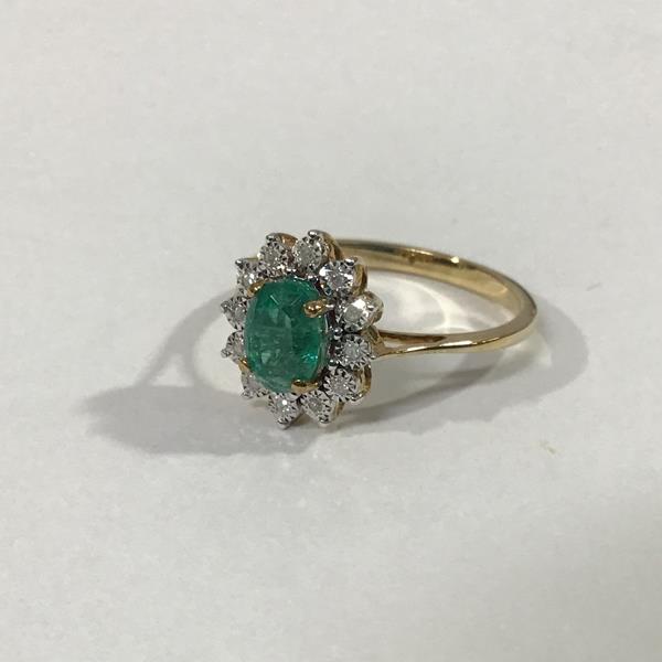 An emerald and diamond cluster ring, the oval-cut emerald claw-set within a band of twelve round