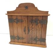 A small Arts & Crafts mahogany and oak hanging cupboard, with shaped pediment over a pair of planked