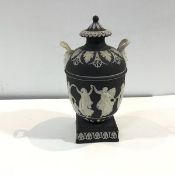 A Wedgwood black dip jasper urn and cover, c. 1900, sprigged with a band of female figures, on a