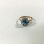 A 9ct gold zircon and diamond cluster ring, the oval-cut blue zircon claw-set within a band of