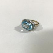 A 9ct gold blue zircon dress ring, the oval-cut stone claw-set within a band of round-cut stones, on