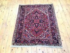 A Hamadan rug, the madder field with central foliate medallion and ivory spandrels, enclosed by