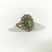 A 9ct gold peridot and seed pearl cluster ring, in Edwardian style, the central oval-cut peridot