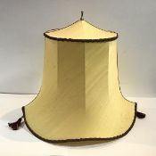 A yellow raw silk lampshade of pagoda shape, with brass final and suspending twin red silk