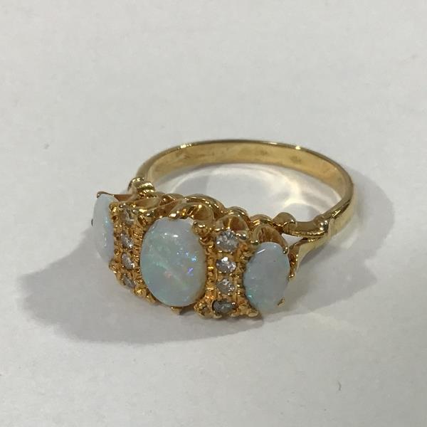 An opal and diamond ring, the three graduated oval opals spaced by twin lines of four diamond points
