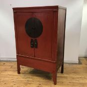 A Chinese red painted marriage cabinet, with a pair of cupboard doors applied with engraved brass