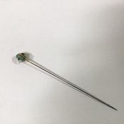 An Edwardian 15ct gold and turquoise hat pin, the irregular turquoise "pebble" enclosed within a