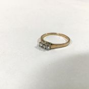 A three stone diamond ring, the uniform round brilliant-cut stones claw-set on a yellow metal band