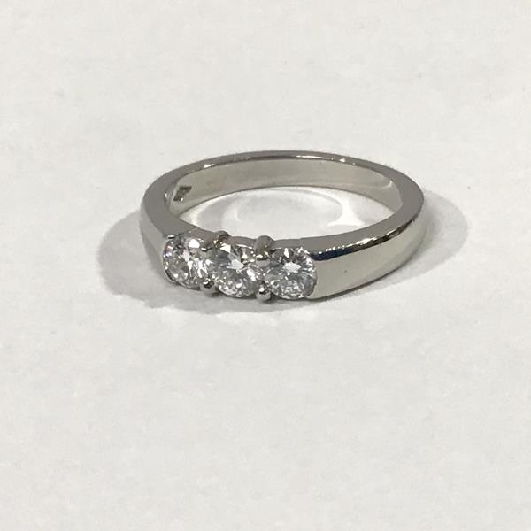 A platinum three stone diamond ring, the uniform round brilliant-cut stones set on a tapering band