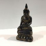 A black and gilt lacquered wooden figure of Buddha, possibly Thai, modelled seated. 23cm