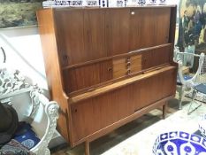 A Danish living room cabinet, 1960's, the raised back incorporating sliding and tambour doors, a