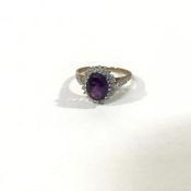 An amethyst and diamond ring, the oval-cut amethyst claw-set within a band of diamond points, on
