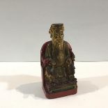 A Chinese gilt and red lacquered figure of a sage, modelled seated on a throne chair. (losses).