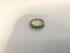 An emerald and diamond ring, the five round-cut emeralds spaced by four pairs of diamond points,