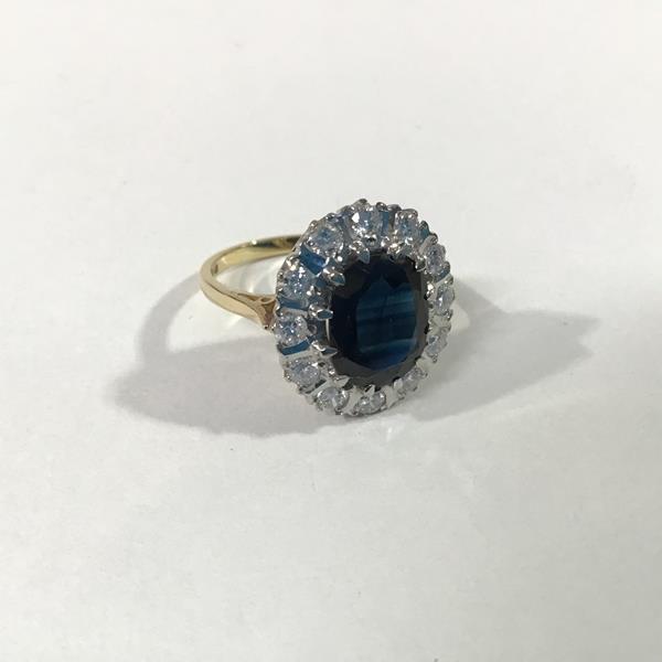 An 18ct gold sapphire and diamond cluster ring, the oval-cut sapphire within a band of twelve