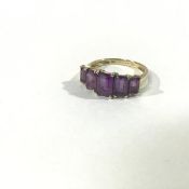 A 9ct gold five stone amethyst ring, the graduated baguette-cut stones on a yellow tapering band.