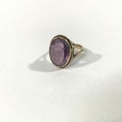 A single stone amethyst ring, the oval-cut stone collet-set within a beaded mount on a 9ct yellow