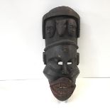 A wooden ethnographic mask, possibly East African, the face with bared teeth and the lips with red
