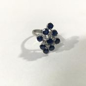 A sapphire and diamond cluster ring, the nine round-cut sapphires claw-set in a navette pattern, the