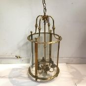 A large brass hall lantern in 19th century style, cylindrical, of four bowed glass panels (one glass