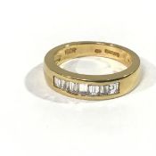 A seven stone diamond ring, the uniform baguette cut stones channel set in a broad 18ct yellow