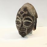 A Chokwe (Congo) carved wooden mask, with insiced geometric decoration and suspending tube bead "