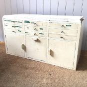 An early 20th century white painted table cabinet, the rectangular top above nine short drawers with