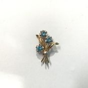 A 9ct gold floral spray brooch, set with three round-cut blue zircons, each in a white metal petal