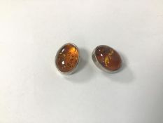 A pair of amber clip earrings within oval silver mounts (2cm x 1.5cm)