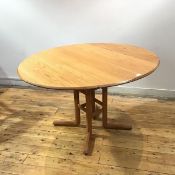 An Ercol elm dining table, the hinged oval top with lunette carving to the frieze, raised on