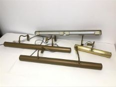 A set of three fluorescent tube picture wall lights, the tubular shades painted golden brown with