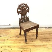 A late Victorian oak hall chair, the pierced cartouche shaped back with central rosette enclosed