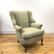 An upholstered wing armchair in the Georgian style, the upholstered back, arms and seat with close