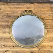 A mid 20thc gilt wood wall mirror, the circular plate within a moulded frame embellished with a