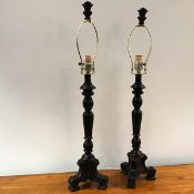 A pair of ebonised table lamps of baluster form, on a tripod base, with matching finial to top of