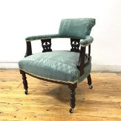 A late 19thc ebonised tub chair, the raised back and upholstered arms supported by pierced splats,