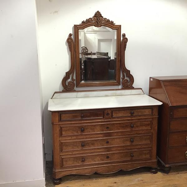 A mid 19thc French walnut and marble topped commode, the moulded top with canted angles above two