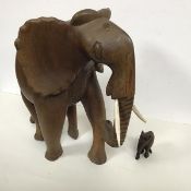 A carved hardwood elephant with bone carved tusks and a smaller carved elephant (missing tusks) (