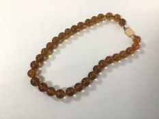 An amber glass bead necklace with a 10ct gold clasp (19cm)