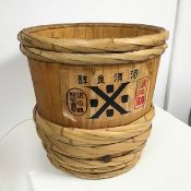 A large wooden bucket with cane straps to upper edge and base allowing for a protruding bung,