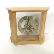 A modern mantel clock, the ring dial with roman numerals and an exposed mechanism, held within a
