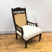 A late 19thc. mahogany armchair, the foliate carved top rail above a fabric back and cushion seat,