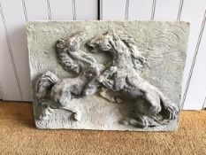 A reconstituted stone panel depicting Two Stallions Fighting in relief, weathered, with some